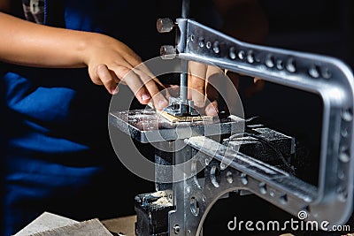 young man cuts a pattern on plywood with an electrical fretsaw Stock Photo