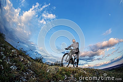 Young man cycling on a rural road through meadow Stock Photo