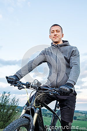 Young man cycling on a rural road through meadow Stock Photo