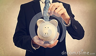 Young man depositing money in piggy bank Stock Photo