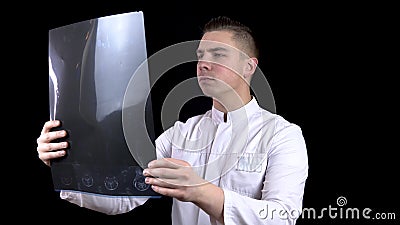 A young man doctor checks the results of an MRI scan of a spine. A man examines an MRI image then shows a thumb down Stock Photo