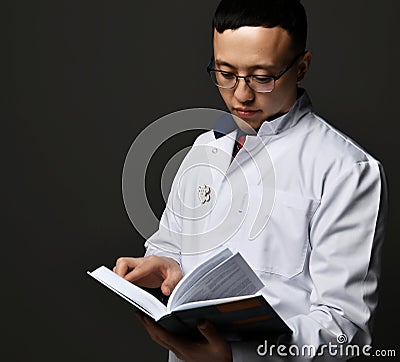 Young man doctor read book. Medicine worker. Healthcare concept on dark Stock Photo