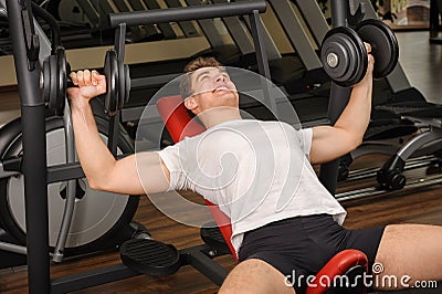 Young man doing Dumbbell Incline Bench Press workout in gym Stock Photo