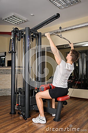 Young man doing lats pull-down workout in gym Stock Photo