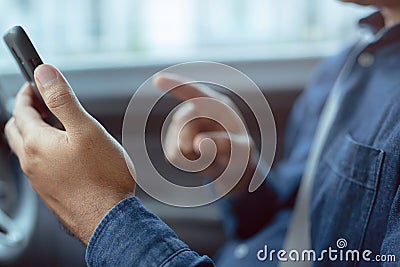Young man driving using mobile smart phone while driving the car. Stock Photo