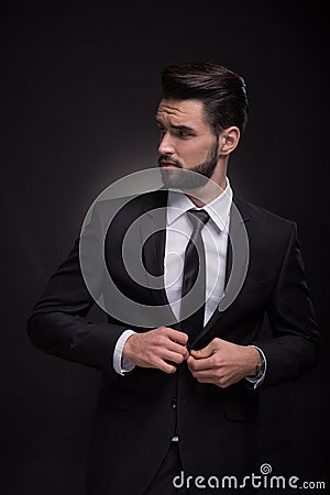 Young man elegant suit buttoning, looking sideways Stock Photo