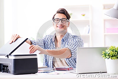 The young man employee working at copying machine in the office Stock Photo