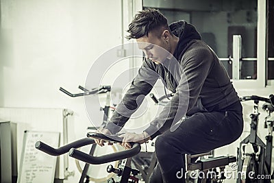 Young man exercising in gym: spinning on stationary bike Stock Photo