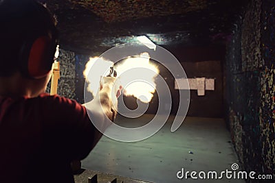 Young man firing a gun at a shooting range the precise moment of Stock Photo