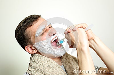 Young man with foam beard and eyebrows singing into the tooth brush Stock Photo