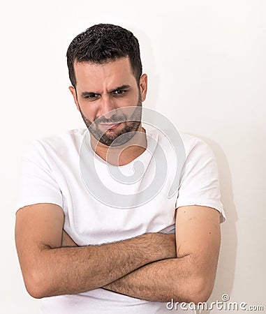 Young man with folded hands, looks angry Stock Photo