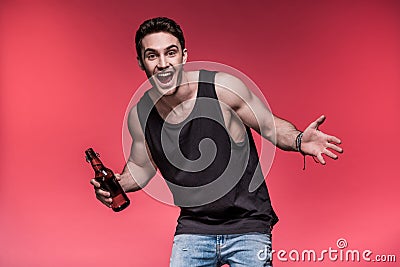 Young man gesturing with beer bottle and smiling at camera Stock Photo