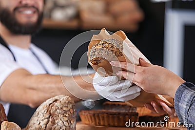 Young man giving fresh bread to woman in bakery Stock Photo