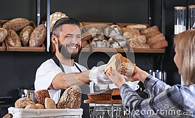 Young man giving fresh bread to woman in bakery Stock Photo