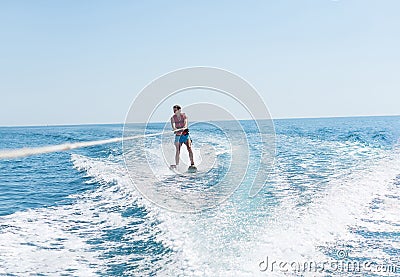 Young man glides on water skiing on the waves on the sea, ocean. Healthy lifestyle. Positive human emotions, feelings, Stock Photo