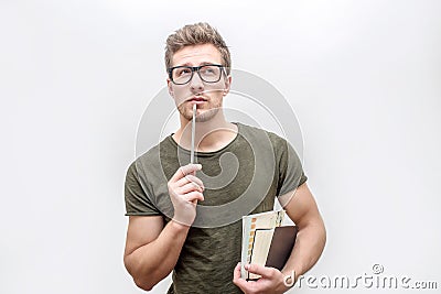 Young man in green shirt hold books and pencil in hands. He looks on camera through glasses. Isolated on white Stock Photo
