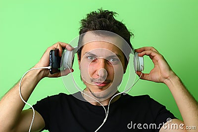 A young man or guy with a positive, inspired charged emotion is listening loudly to music against a light green Stock Photo