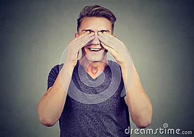 Young man with hands on eyes in anticipation of a pleasant surprise Stock Photo