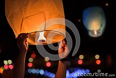 Young man hands release sky lanterns on festival. Warm light from fire Stock Photo