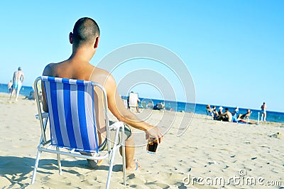 Young man hanging out on the beach, with a glass with cola drink Stock Photo