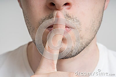 Young man has finger on lips and showing be quiet gesture Stock Photo