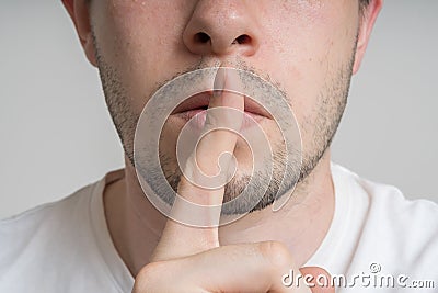 Young man has finger on lips and showing be quiet gesture Stock Photo