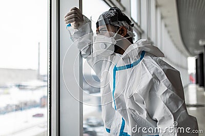 Young man in Hazmat protective suits look glass at home or office during outbreak of Coronavirus, Covid-19 Stock Photo