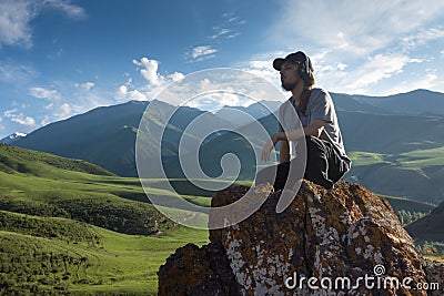 Young man in headphones listening music in nature and at the mountain Stock Photo