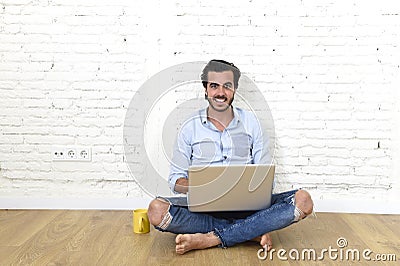 Young man in hipster modern casual style look sitting on living room home floor working on laptop Stock Photo