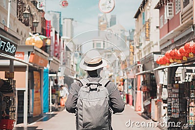 Young man hipster traveling with backpack and hat, happy Solo traveler walking at Chinatown street market in Singapore. landmark Stock Photo