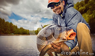 Young man hold big carp in his hands. Stock Photo