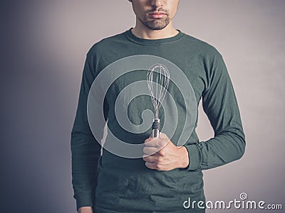 Young man holding a balloon whisk Stock Photo