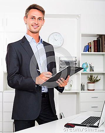 Young man holding clipboard in office Stock Photo
