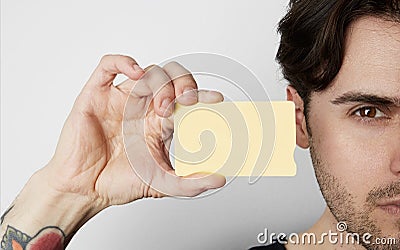 Young man holding empty yellow color credit card close of male face on blank white background. Business mock-up Stock Photo