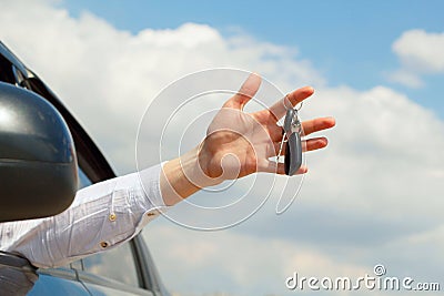 Young man holding keys remote from his car in hands over sky background Stock Photo