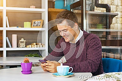 Young man holding a mobile phone and smiling Stock Photo