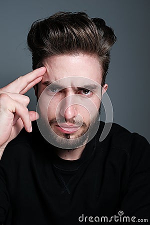 A young man holds his head and shows different human emotions: hatred, fear, despair, horror, malaise, headache, clairvoyance. Stock Photo