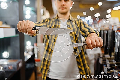 Young man holds kitchen knives in houseware store Stock Photo