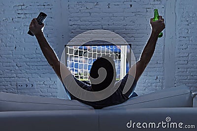 Young man home alone watching soccer or football game in television enjoying and celebrating goal Stock Photo