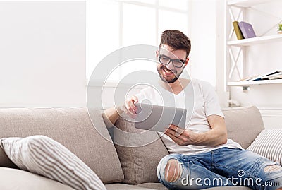 Young man at home reading on tablet Stock Photo