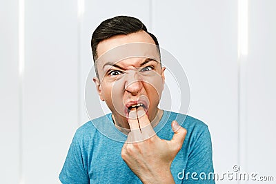 Young man inserts two fingers in the mouth to induce vomiting Stock Photo