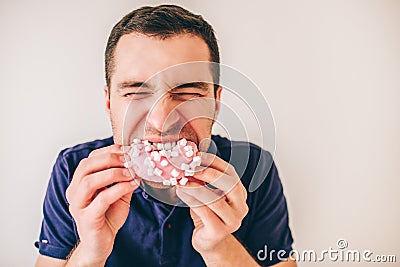 Young man isolated over background. Guy biting pink donut piece with pleasure. Hungry person divour meal. Portrait of Stock Photo