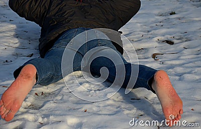 Young man in jeans running away barefoot in the snow. Detained by police lying on the ground with his hands behind his back, no sh Stock Photo