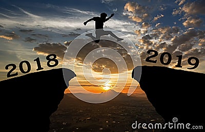 A young man jump between 2018 and 2019 years over the sun and through on the gap of hill silhouette Stock Photo