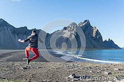 Young man jumping in the black sand beach of Stokksnes Peninsula. Iceland Stock Photo