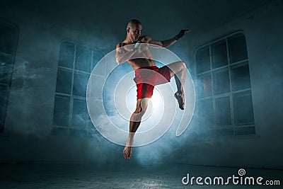 The young man kickboxing in blue smoke Stock Photo