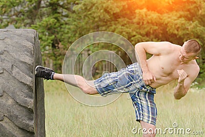 Young man is kicked a foot in a tire. Workout Stock Photo