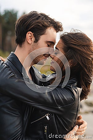 Man kissing brunette girlfriend in leather Stock Photo