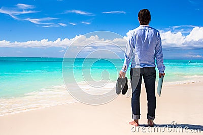 Young man with laptop on the background of turquoise ocean at tropical beach Stock Photo