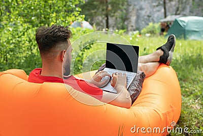 young man with laptop working outdoor. Freedom, remote work, freelancer, technology, internet, travel, vacation concepts Stock Photo